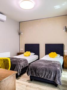 two beds in a room with yellow pillows on them at GRONO Apartamenty in Częstochowa