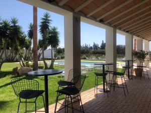 a patio with tables and chairs and palm trees at Hacienda Soto-Hego Haizea in Chiclana de la Frontera