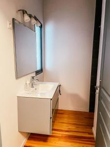 y baño con lavabo blanco y espejo. en Bel appartement T3 avec terrasse, en Carmaux