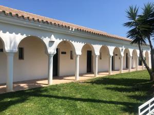a row of arches on a building with a palm tree at Hacienda Soto-Hego Haizea in Chiclana de la Frontera