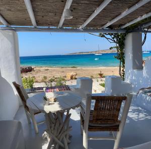 庫福尼夏島的住宿－Palio Karnagio Παλιό Καρνάγιο，一张桌子和椅子,享有海滩美景