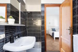 Łazienka z białą umywalką i czarnymi kafelkami w obiekcie Casa Platano - Private pool - Ocean View - BBQ - Garden - Terrace - Free Wifi - Child & Pet-Friendly - 4 bedrooms - 8 people w mieście Poris de Abona