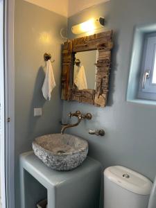 a bathroom with a stone sink and a mirror at Palio Karnagio Παλιό Καρνάγιο in Koufonisia