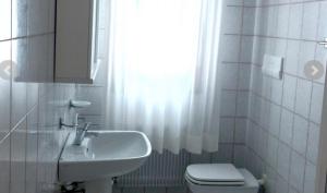a bathroom with a sink and a toilet and a window at Villa Rosa in Lignano Sabbiadoro