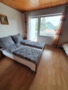 a bedroom with a bed and a large window at Wolf Vendégház in Balatonkeresztúr