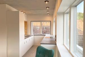 a kitchen with white walls and a green chair at Serviced Apartments - Penthouse im Herzen Königsbronns in Königsbronn