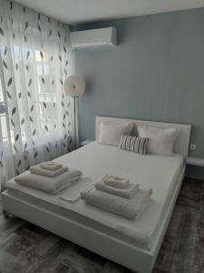 a white bed with two folded towels on it at Villa Valentines in Kiten