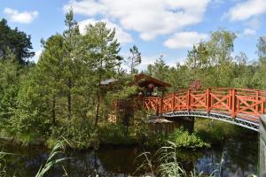 a red bridge over a river with a building at Agroturystyka Żabi Dwór in Ostrzyce