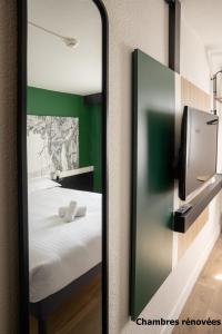 格拉迪尼昂The Originals City Hôtel Bordeaux Porte du Bassin的一张床铺和一面绿色的墙壁,镜子在房间里 更多37张照片