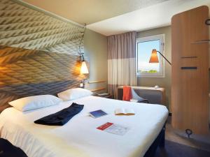 Habitación de hotel con cama blanca grande y ventana en ibis Archamps Porte de Genève en Archamps