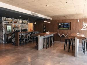 a bar in a restaurant with wooden walls and stools at ibis Pilar in Pilar