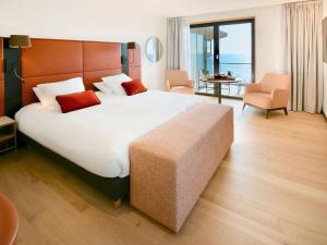 a hotel room with a large bed and a couch at Sainte-Barbe Hôtel & Spa Le Conquet - MGallery in Le Conquet