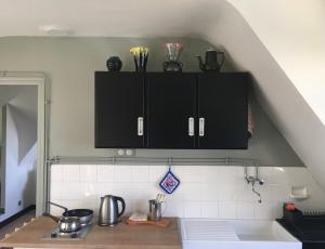 a kitchen with black cabinets with utensils on it at Maison BelleMondo in Criel-sur-Mer +22 photos