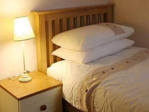 a bed with white pillows and a table with a lamp at Hebridean Guest House in Stornoway