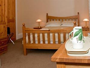 a bedroom with a wooden bed and a wooden table at Hebridean Guest House in Stornoway