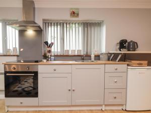 cocina con armarios blancos, fregadero y horno en Ditsys Den en Tonbridge