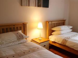 a bedroom with two beds and a lamp on a table at Hebridean Guest House in Stornoway