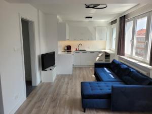 uma sala de estar com um sofá azul e uma cozinha em Słoneczny Apartament przy Filharmonii, Wałach Chrobrego em Szczecin