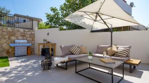 a patio with a couch and an umbrella at Apartments Villa Frankola with swimming pool in Crikvenica