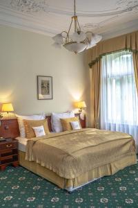 um quarto com uma cama grande e um lustre em Hotel Mignon em Karlovy Vary