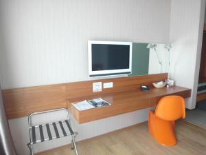 a room with a desk with a tv and a chair at French Hotel in Ipoh