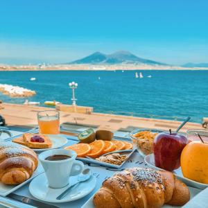 Relais sul Mare Boutique Hotel في نابولي: طاولة مع افطار من خبز وفواكه وقهوة