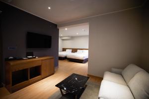 a room with two beds and a couch and a tv at Hotel The Star in Yeonggwang