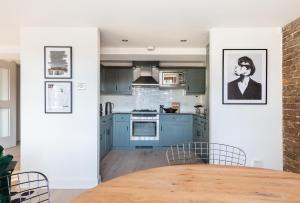 a kitchen with blue cabinets and a wooden table at The Wapping Wharf - Modern & Bright 2BDR Flat on the Thames with Parking in London