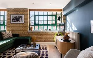ein Wohnzimmer mit grüner Couch und blauen Wänden in der Unterkunft The Wapping Wharf - Modern & Bright 2BDR Flat on the Thames with Parking in London