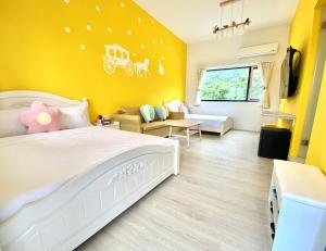 - une chambre avec un lit blanc et un mur jaune dans l'établissement Blue and White Style Holiday B&B, à Guanshan