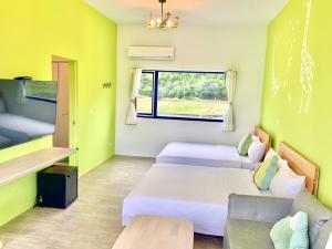 Cette chambre comprend deux lits, un canapé et une fenêtre. dans l'établissement Blue and White Style Holiday B&B, à Guanshan