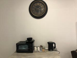a clock on a wall above a microwave and a toaster oven at The Guesthouse Klerksdorp in Klerksdorp