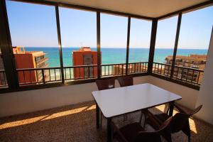 een tafel en stoelen in een kamer met uitzicht op de oceaan bij Apartamento Arenales in Arenales del Sol