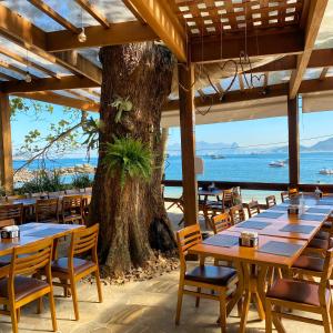um restaurante com mesas e cadeiras e uma árvore em Pousada Camarote Itaipu em Niterói