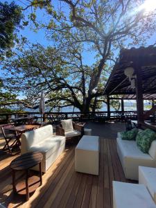 a deck with couches and tables and a tree at Pousada Camarote Itaipu in Niterói