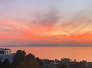 einen Sonnenuntergang über einem Wasserkörper mit einer Stadt in der Unterkunft On the GBay Villa in Gordonʼs Bay