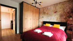 a bedroom with a red bed with towels on it at Residence Polanica z sauną, Sun & Snow in Polanica-Zdrój