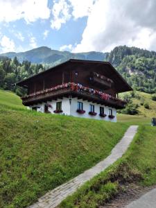 a building on a hill with flowers on it at Bio-Bauernhof Schiederhof in Fusch an der Glocknerstraße