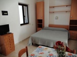 a bedroom with a bed and a tv and a table at Case vacanze Villa Elisa in Vieste