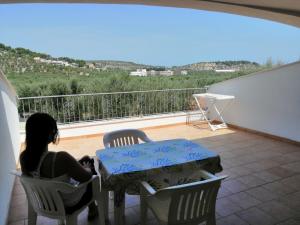 a woman sitting at a table on a balcony at Case vacanze Villa Elisa in Vieste
