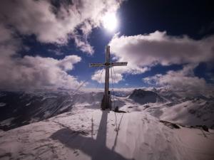 uma cruz no topo de uma montanha coberta de neve em Appartement Berghof em Saalbach-Hinterglemm