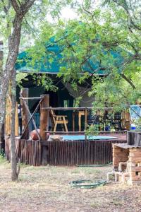 una casa con un árbol y una silla delante de él en Beka Idube Bushveld Retreat, en Cullinan