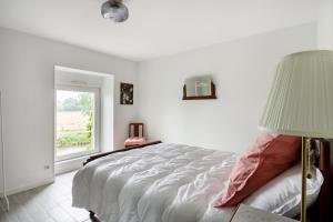 una camera bianca con un letto e una finestra di Le Clos Saint-Pierre a Poilley