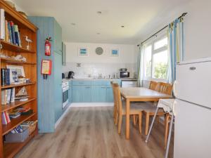 a kitchen with blue cabinets and a table with chairs at Trevone - Chalet 130 in Padstow