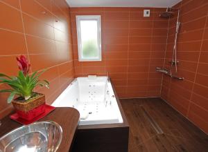 a bathroom with a bath tub and a sink at Au Pré Carré in Plumergat