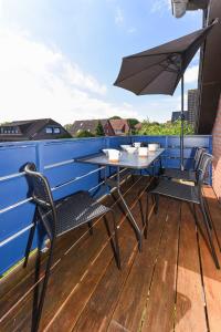 einen Tisch und Stühle auf einem Balkon mit Sonnenschirm in der Unterkunft Ferienwohnungen Friesenhuus in Neuharlingersiel