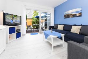 ein Wohnzimmer mit einem blauen Sofa und einem TV in der Unterkunft Ferienwohnungen Friesenhuus in Neuharlingersiel