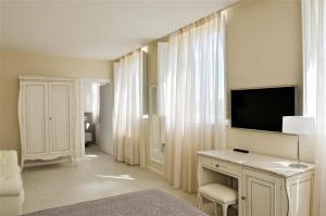 a living room with a television and a desk with a chair at Villa del Sole Siena in Siena
