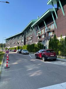 a parking lot with cars parked in front of a building at Luxury Silver Mountain Apartment in Poiana Brasov