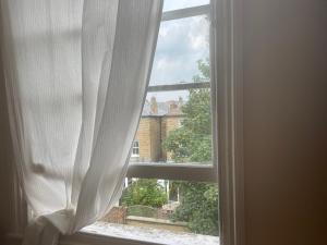 an open window with a view of a house at Guest House quarto Individual cama box solteiro ! Finsbury Park in London
